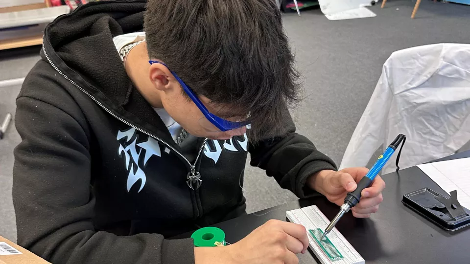 A student works on learning how to solder computer circuitry.