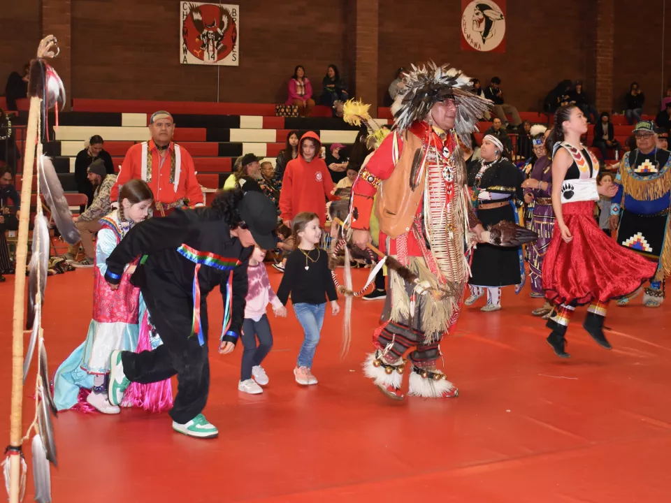 Photo of a powwow in a high school gymnasium.