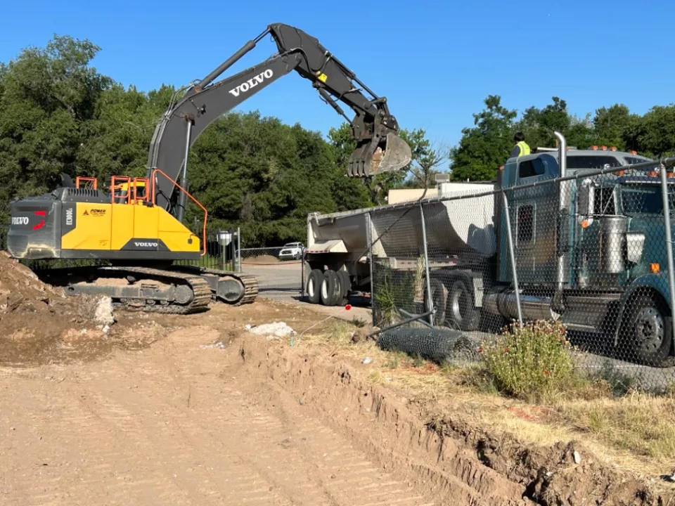 Loading trucks with concrete at Ohkay Owingeh Community School demolition site. A yellow loading trucks lifts concrete into a construction truck. 