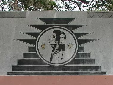 A photo of a logo of an Indigenous man faced sideways onto a grey slab.