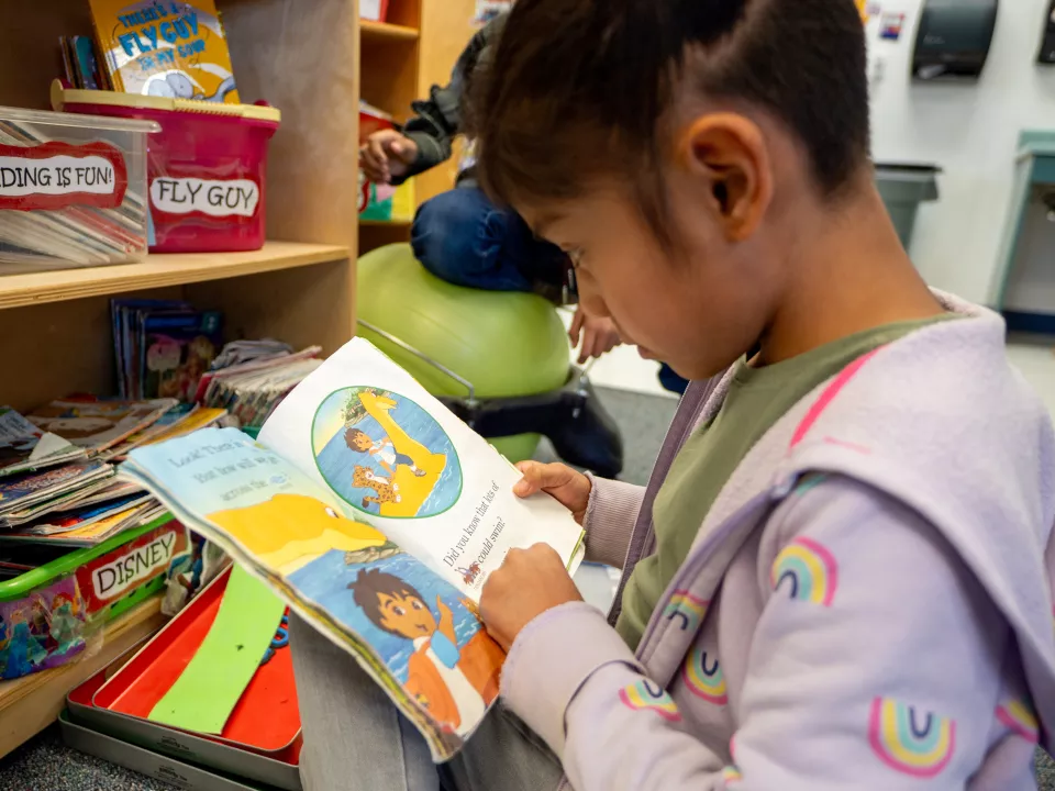 An elementary school student looks at a picture book.