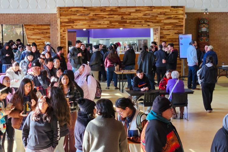 A huge group of college students gather outside a coffee shop.