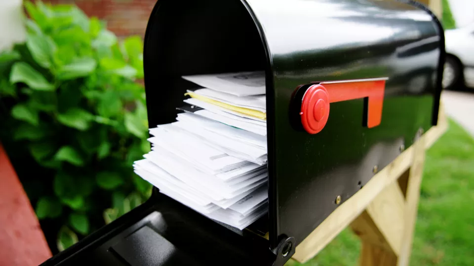 An open mailbox with a stack of white envelopes in it.