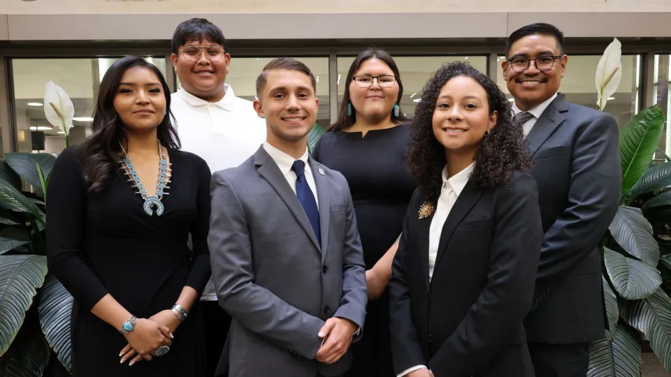 Six young people in professional dress pose for a photo together.