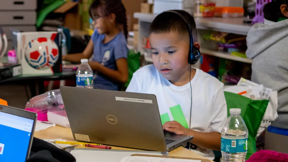 A student on a laptop and wearing headphones.