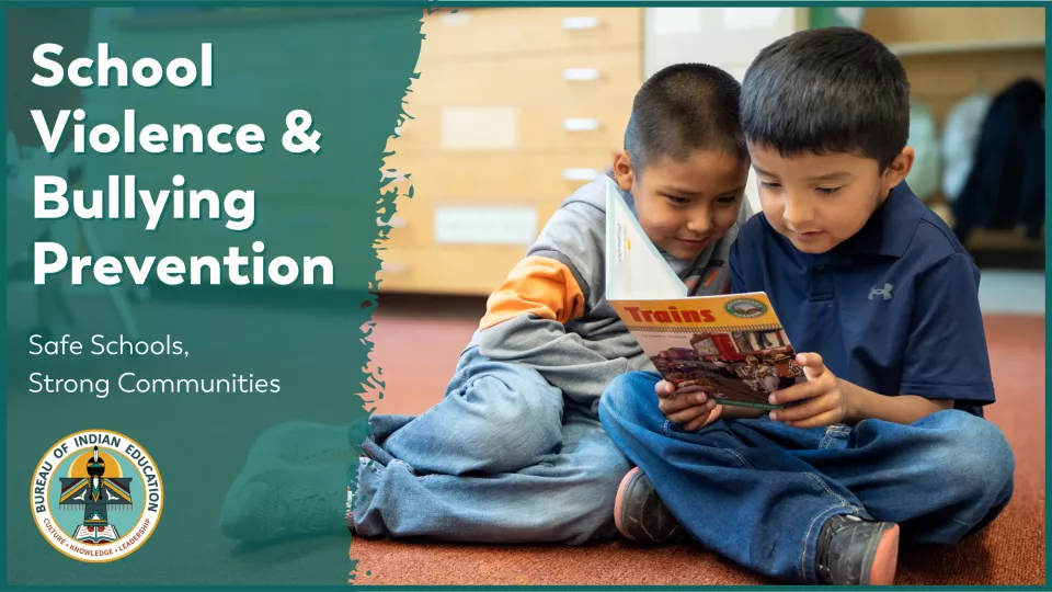 Two young students sit together on the floor and read a book.