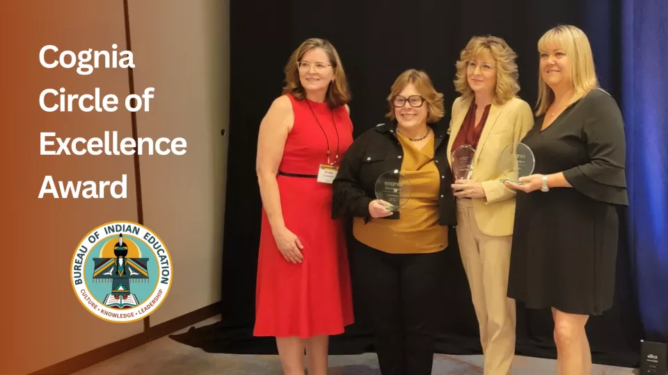 Four women stand in a row getting their picture taken while holding awards.