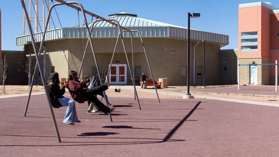 A group of students on the playground swings.