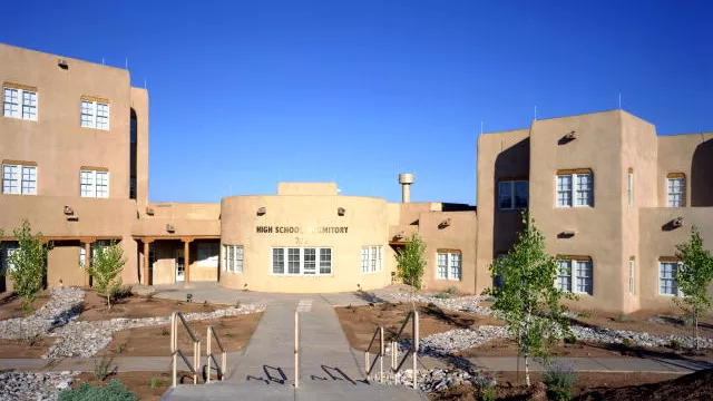 A wide shot of a high school against a bright blue sky.