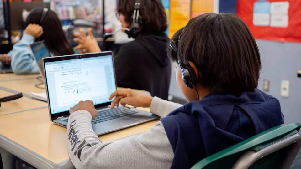 A student works on a laptop at a desk.