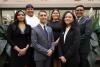 Six young people in professional dress pose for a photo together.